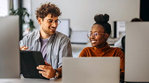 Two people looking at computers and smiling